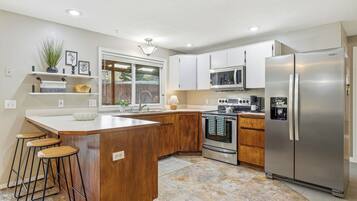 Een moderne keuken met een centraal eiland, houten kastjes, roestvrijstalen apparatuur en een grote koelkast.