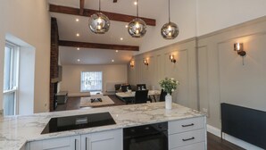 A modern kitchen with a marble countertop, built-in oven, and a ceiling fan. - The Penthouse at 86 (Rossendale)