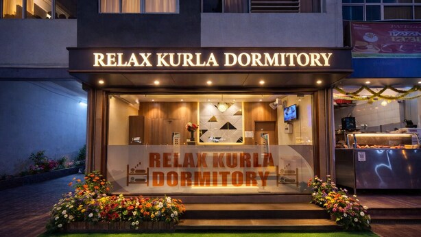 Exterior de la Residència Relax Kurla, amb una zona de recepció, una pantalla de televisió i una presentació floral.