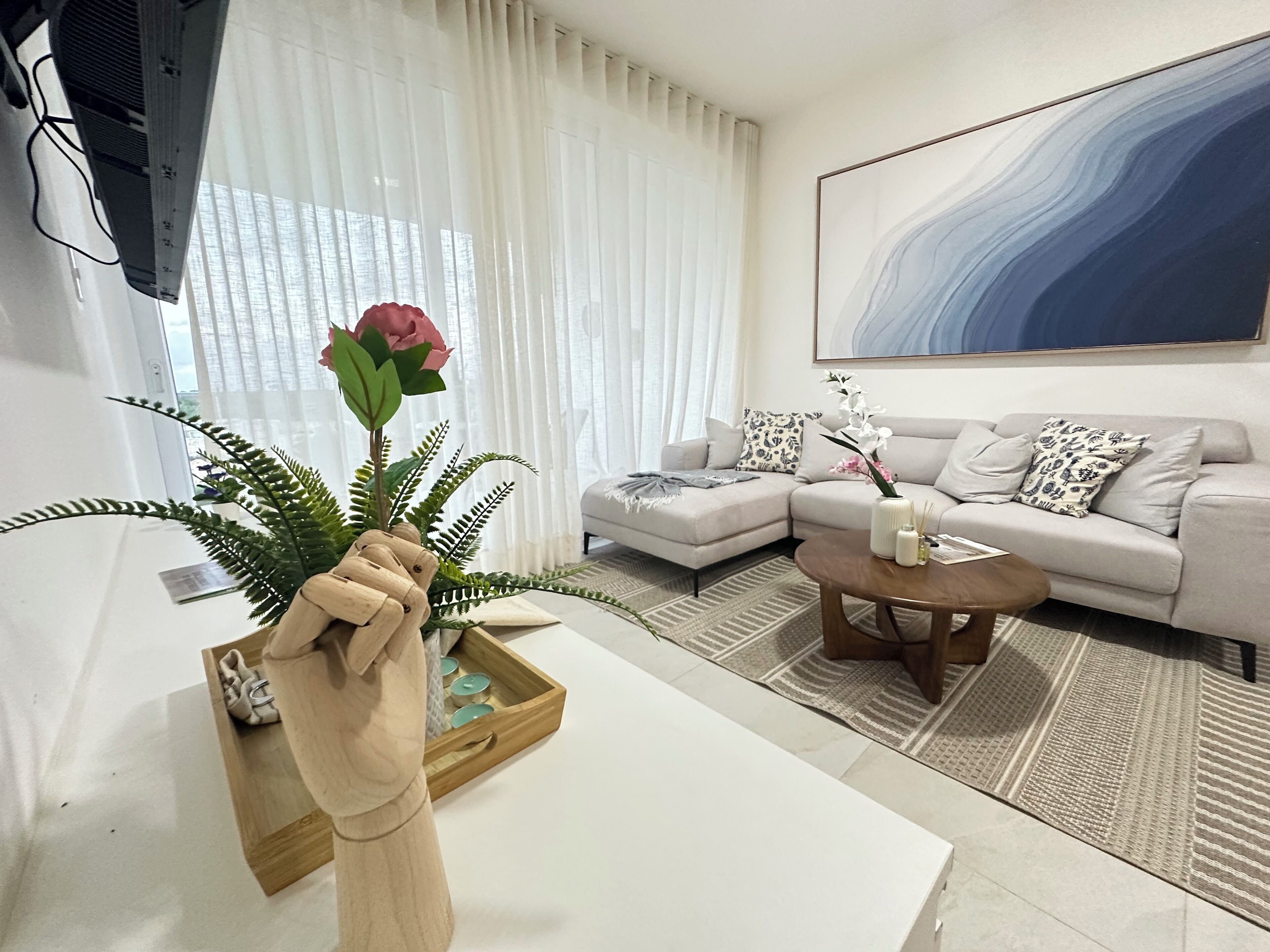 A modern living room with a sectional sofa, a coffee table, and a large abstract painting on the wall.