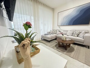 Ein modernes Wohnzimmer mit einem Ecksofa, einem Couchtisch und einem großen abstrakten Gemälde an der Wand.