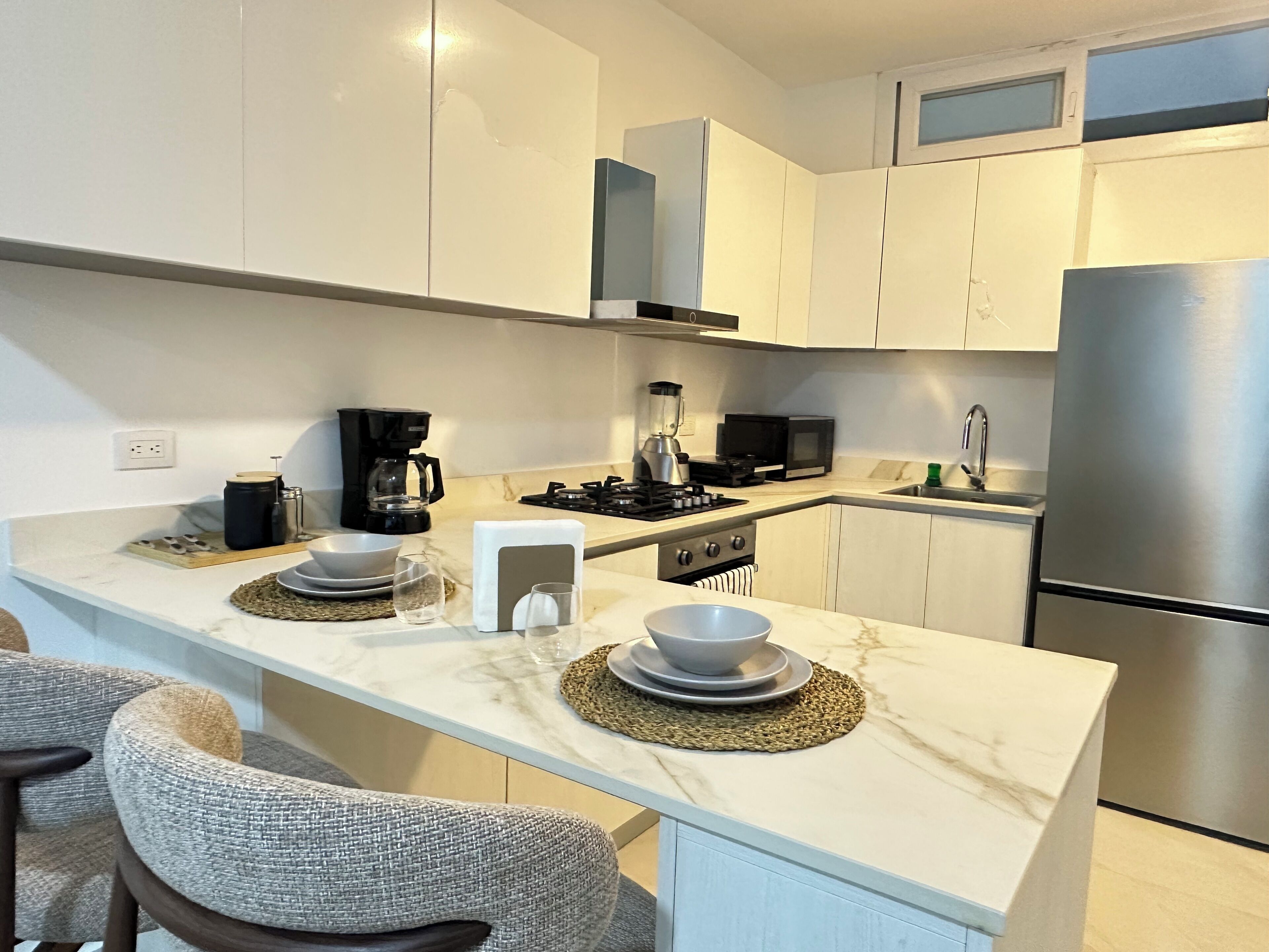 A modern kitchen with white cabinets, a stainless steel refrigerator, a gas stove, and a microwave.