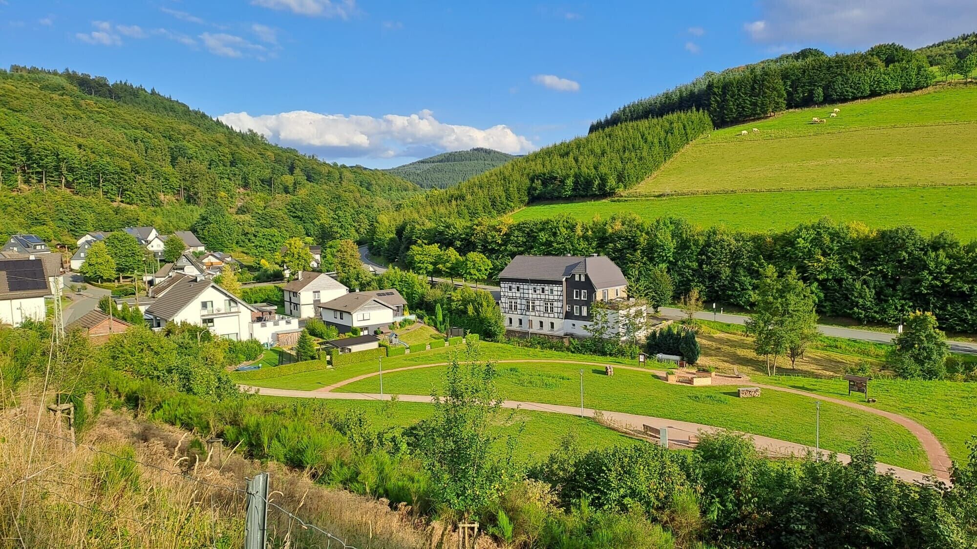 Un pueblo rural con casas, un edificio grande y un valle verdeado.