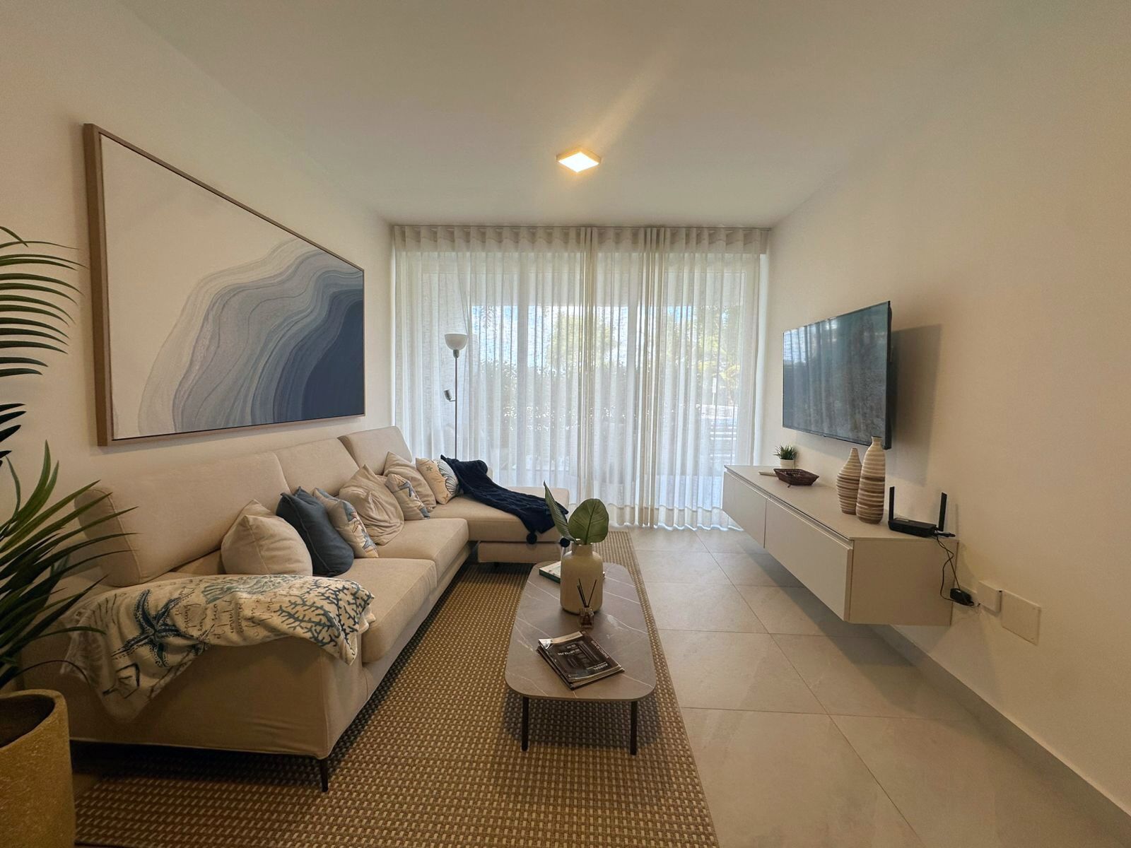 Ein modernes Wohnzimmer mit einer Couch, einem Couchtisch und einem an der Wand befestigten Fernseher.
