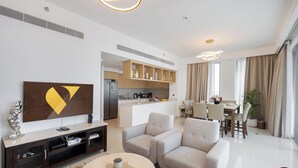 Een moderne woonkamer met een flatscreen televisie, een bank, een salontafel en een eethoek met een tafel en stoelen.