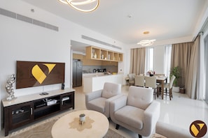 Ein modernes Wohnzimmer mit Flachbildfernseher, einer Couch, einem Couchtisch und einem Essbereich mit Tisch und Stühlen.