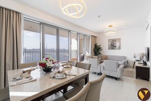 Un salon moderne avec un coin repas, de grandes fenêtres offrant une vue sur la ville et un décor contemporain.