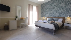 A bedroom with a bed, bedside table, lamp, and a desk with a chair. - B&B Maison de Charme (Pompei)