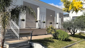 A building with a white facade, a covered entrance with a staircase, and a well-maintained lawn. - B&B Maison de Charme (Pompei)