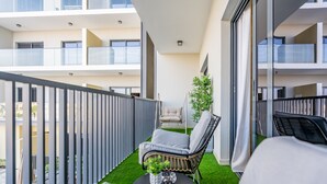 Un balcone con un divano, una poltrona e un tavolino con una pianta.