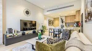 Un soggiorno moderno con divano, tavolino e televisore. Si nota un'area pranzo con tavolo e sedie. In secondo piano si vede la cucina.