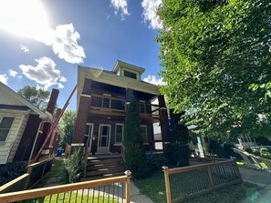 A two-story house with a front porch, a wooden staircase, and a large tree in the yard. - 2 Bedroom Cozy Accomodation (Windsor)