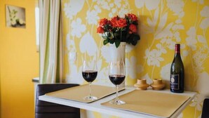 Une table avec deux verres à vin, un vase de fleurs rouges et une bouteille de vin.