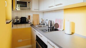Une cuisine compacte avec des meubles blancs, un four à micro-ondes, un grille-pain et une bouilloire.