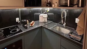 Eine kompakte Küche mit Einbauofen, Kaffeemaschine, Toaster und Spüle.