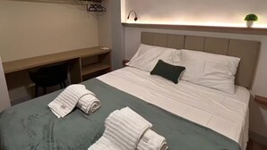 Ein modernes Hotelzimmer mit einem großen Bett, einem Schreibtisch und einer kleinen Pflanze.