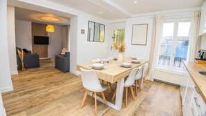 A modern kitchen with a dining area, wooden flooring, and a view of the city.