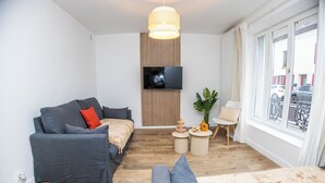 A modern living room with a grey sofa, a small coffee table, and a TV mounted on a wooden panel wall.