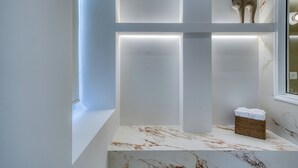 A modern bathroom with a marble countertop, a wicker basket with towels, and a decorative cat figurine. - Nalia Suites (Nafplio)