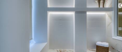 Un baño moderno con encimera de mármol, una cesta de mimbre con toallas y una figurita decorativa de gato.