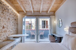Ein Schlafzimmer mit einem Bett, einem kleinen Tisch und zwei Stühlen. Ein Balkon bietet Blick auf Gebäude.