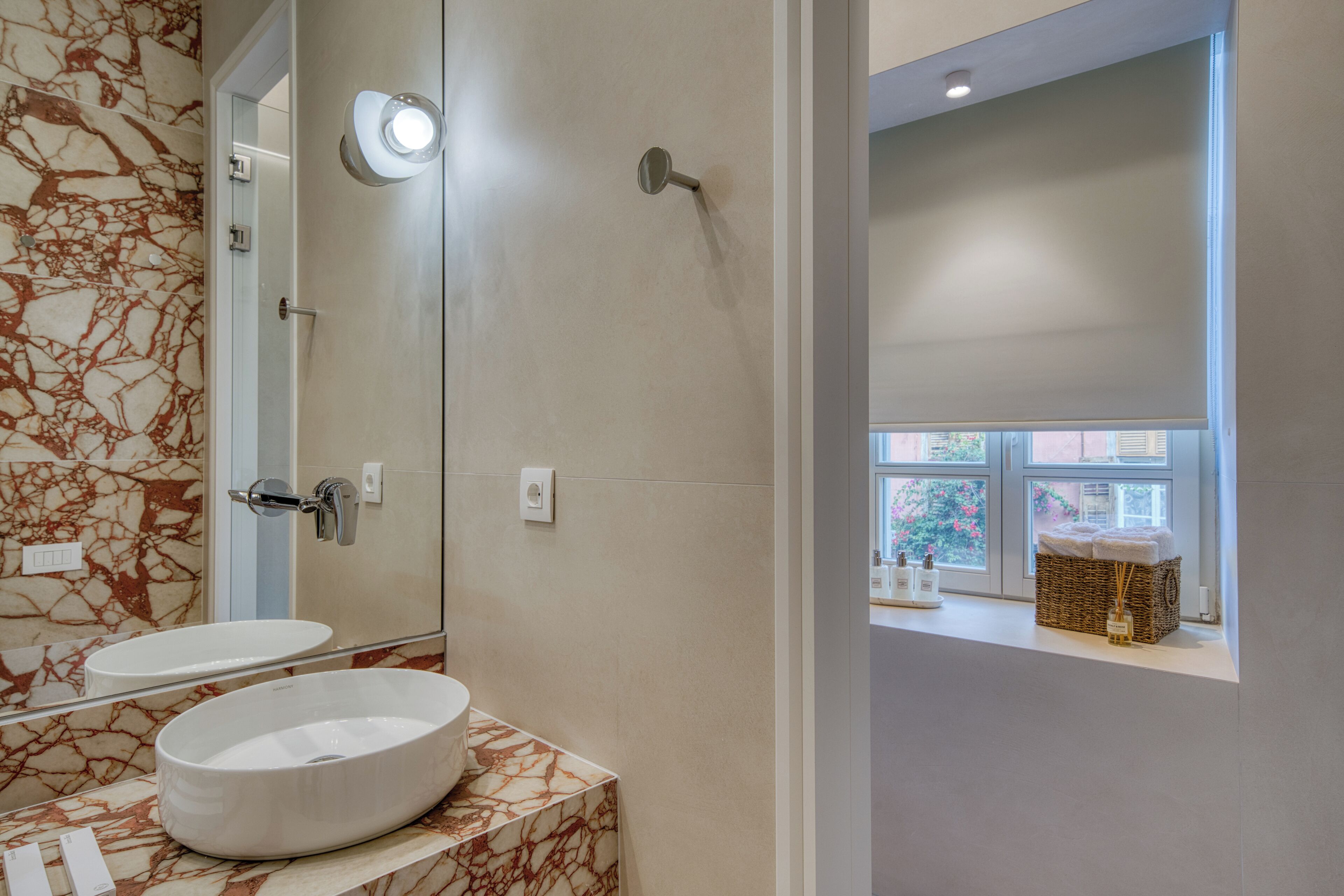 A bathroom with a marble vanity, a large mirror, and a window with a view of the outside.