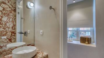 A bathroom with a marble vanity, a large mirror, and a window with a view of the outside.