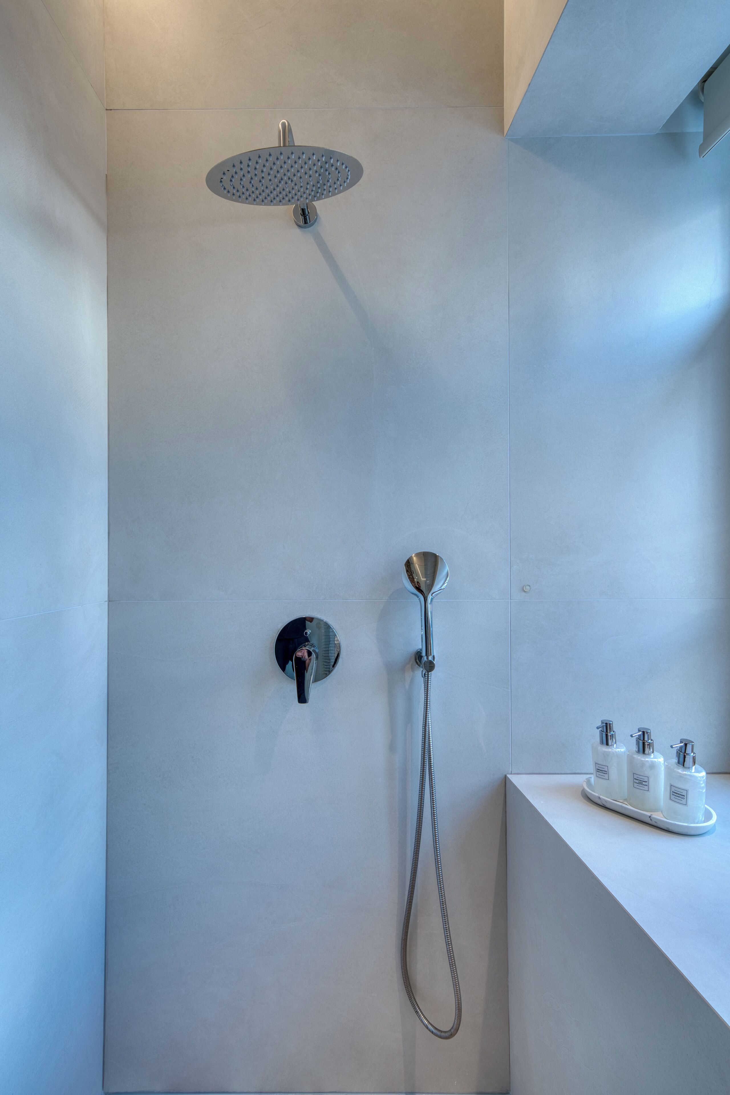 Een moderne douche met een handdouche en een douchekop die aan de muur bevestigd is.