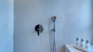 Een moderne douche met een handdouche en een douchekop die aan de muur bevestigd is.