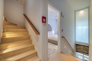 A staircase leading to a bedroom with a bed, a ceiling fan, and a window with a view. - Nalia Suites (Nafplio)