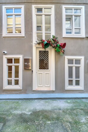A building facade with a central door, multiple windows, and a security camera. - Nalia Suites (Nafplio)