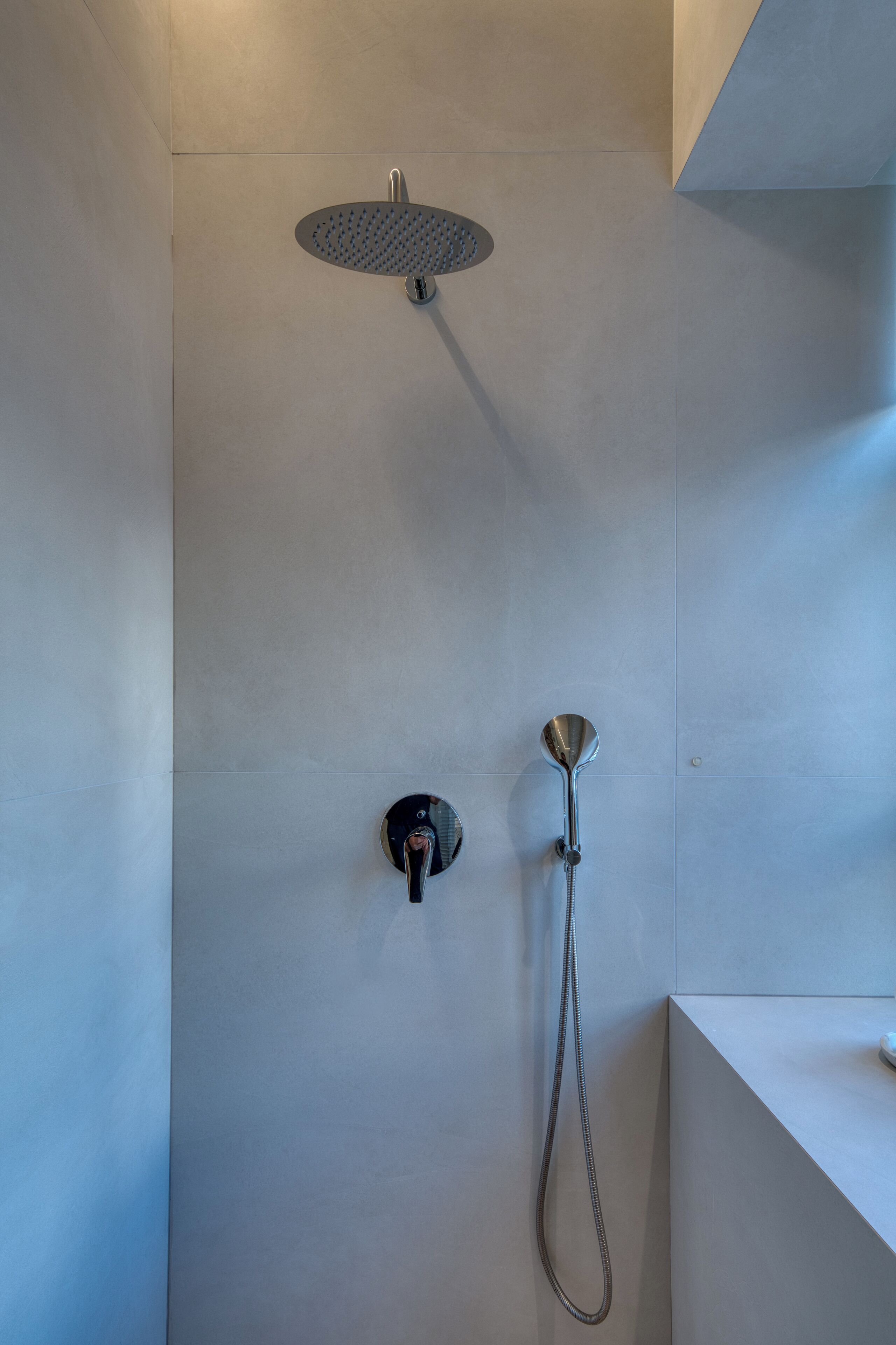 Una ducha moderna con cabezal de ducha manual y un cabezal de ducha tipo lluvia instalado en la pared.
