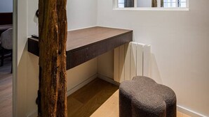 Ein modernes Zimmer mit einem Holztisch, einem kleinen Hocker und einem Fenster mit Vorhängen.
