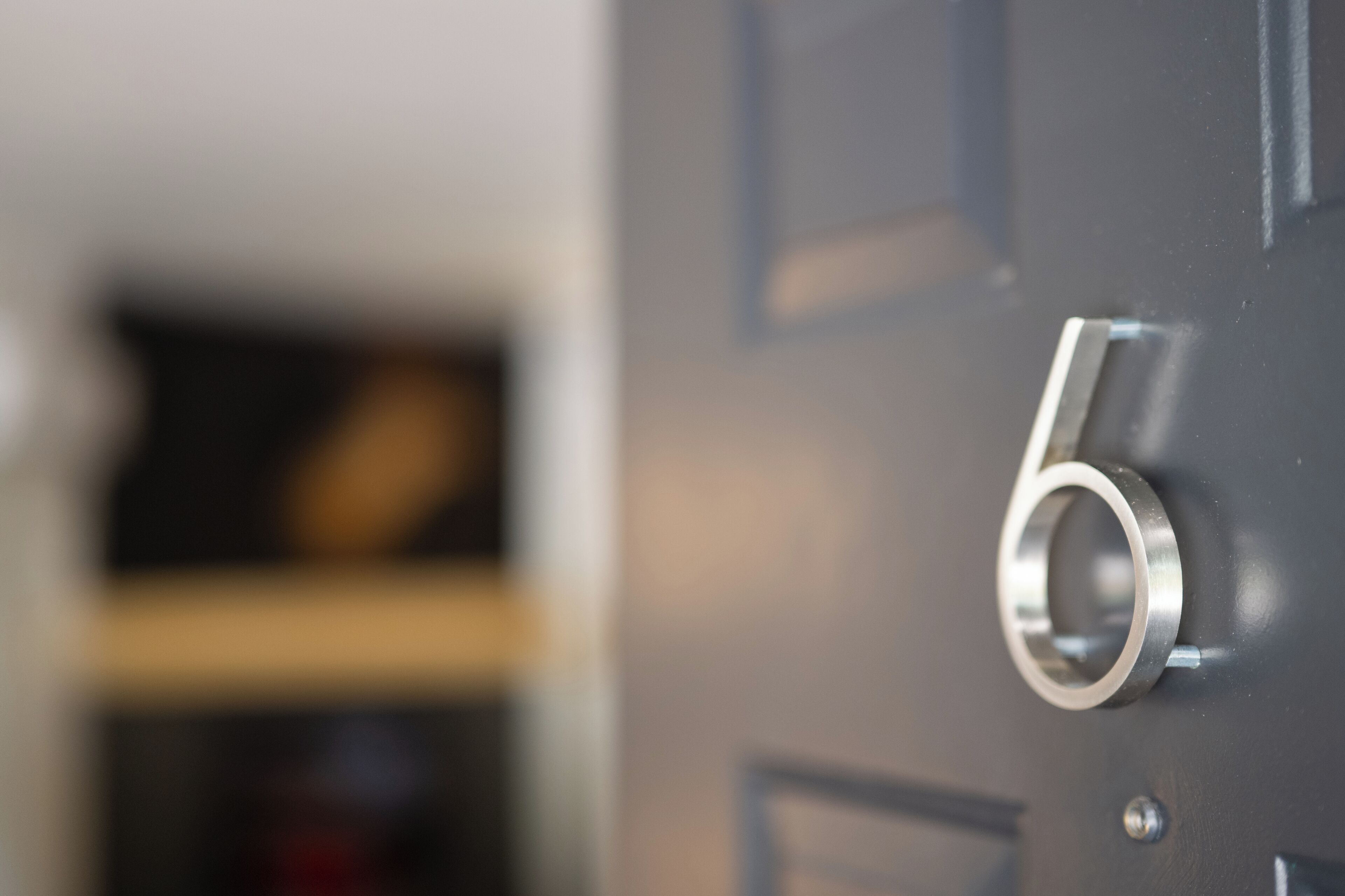 A close-up of a metallic door handle with a number '6' on a dark door.