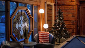 Une pièce chaleureuse avec une table de billard, un sapin de Noël et un mur en bois.