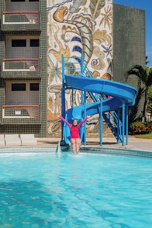 A swimming pool with a blue slide and a mural of sea creatures on the adjacent building. - El Aram Beach Cabo All Inclusive (Cabo de Santo Agostinho)