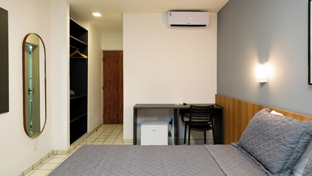 A bedroom with a bed, a desk, a chair, a wardrobe, and an air conditioning unit. - El Aram Beach Cabo All Inclusive (Cabo de Santo Agostinho)