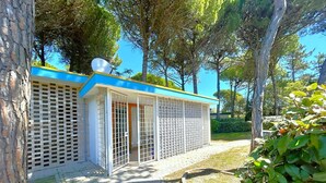 A building with a blue roof, white walls, and a lattice fence. - VILLA NORTH 321B - A2 6+0 - B03215 (Bibione Pineda)