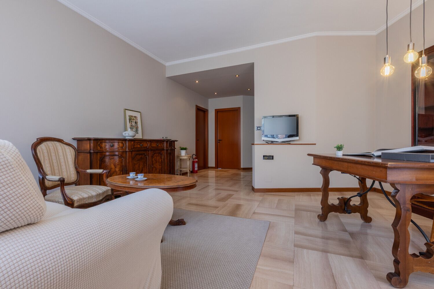Una sala de estar con sofá, una mesa de centro de madera, un televisor sobre un mueble bajo y un armario.