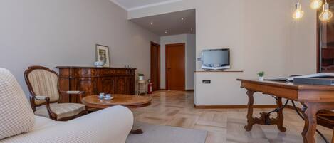 Una sala de estar con sofá, una mesa de centro de madera, un televisor sobre un mueble bajo y un armario.