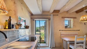 Una cocina con lavamanos, estufa y comedor con mesa y sillas.