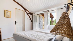 Un dormitorio con una cama, una puerta, un ventanal y una cesta colgante.