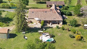 Una casa con techo de tejas, piscina y patio cercado.