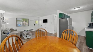 A modern living room with a sofa, a dining table, and chairs. There is a kitchen area with cabinets and a refrigerator. - Enjoyable 1-bedroom apartment with AC in charming Le Claire (Le Claire)