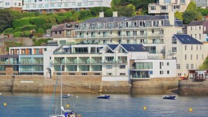 A coastal hotel with multiple floors, balconies, and a marina with boats. - Villa 8, Estura (Salcombe)