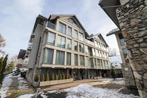 Ein mehrstöckiges Hotel mit einer Stein-Fassade, großen Fenstern und einem überdachten Außenbereich.