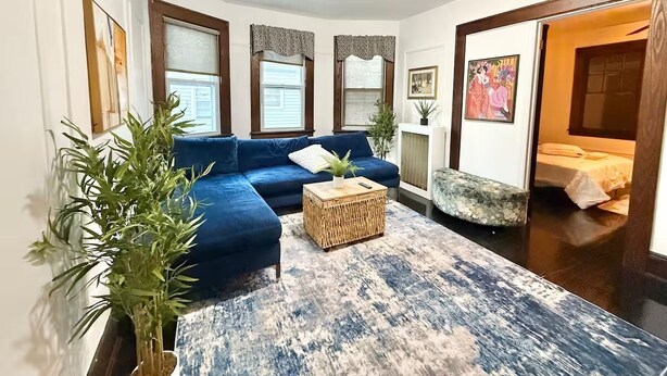 Uma sala de estar com um sofá azul, uma mesa de centro de fibra natural e um tapete azul estampado.