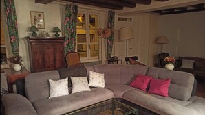 A cozy living room with a sectional sofa, a glass coffee table, and a wooden cabinet.