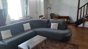 A living room with a grey sectional sofa, a small wooden coffee table, and a patterned rug.