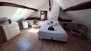 A bedroom with a skylight, a bed, a dresser, a chair, and a desk.